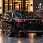Black Mercedes-Benz E-Class chauffeur sedan viewed from the rear at night